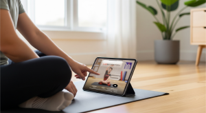 An image of a person using the WeStretch app on a tablet while sitting on a yoga mat in a bright home environment.