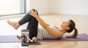 An image of a woman doing a knee-to-chest stretch on a yoga mat.