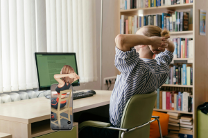An image of a woman doing a seated upper body stretch at her desk to relieve stiffness from prolonged sitting.