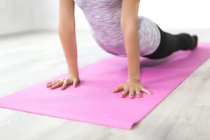 A photo of a person holding a plank position on a yoga mat to support core and lower back strength.