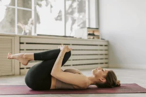 A photo of a person lying on their back performing a knees-to-chest stretch to relieve lower back tension.