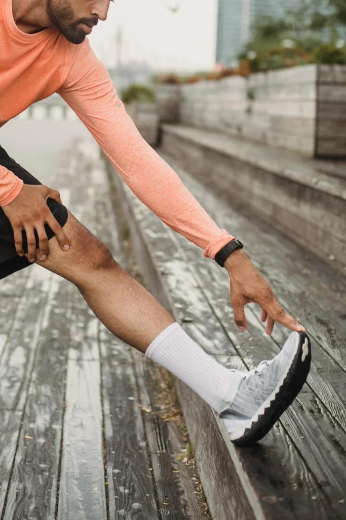 A photo of a runner stretching his hamstring on outdoor steps during cool down stretches after a workout.
