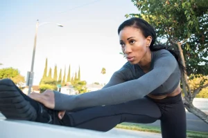 A photo of a runner stretching their leg on a bench as part of a warm-up routine.