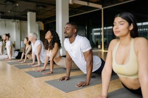 An image of a diverse group of people performing a yoga cobra pose on mats in a studio, focusing on spinal extension and morning mobility.