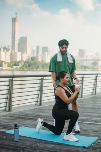 An image of a fitness trainer guiding a woman through a morning lunge exercise to increase energy.