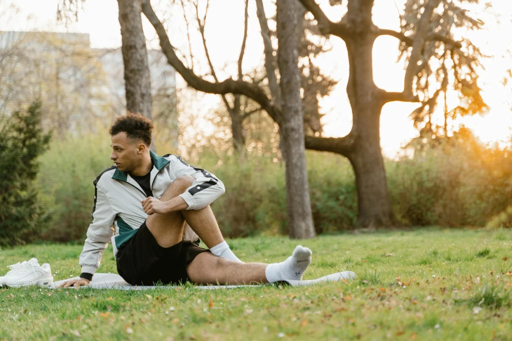 An image of a man doing a seated spinal twist on a mat outdoors as part of a cool-down stretch after exercise.