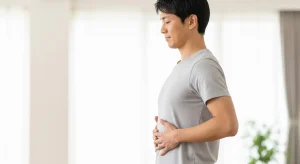 An image of a person gently engaging core muscles with hands on the abdomen.