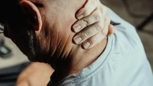 An image of a person holding their neck to relieve tension as part of a daily mobility routine.