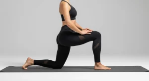 An image of a person performing a half-kneeling hip flexor stretch on a yoga mat