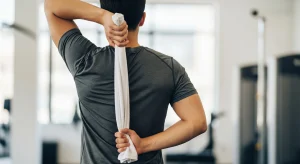 An image of an individual using a towel behind the back for a shoulder mobility stretch, improving flexibility.